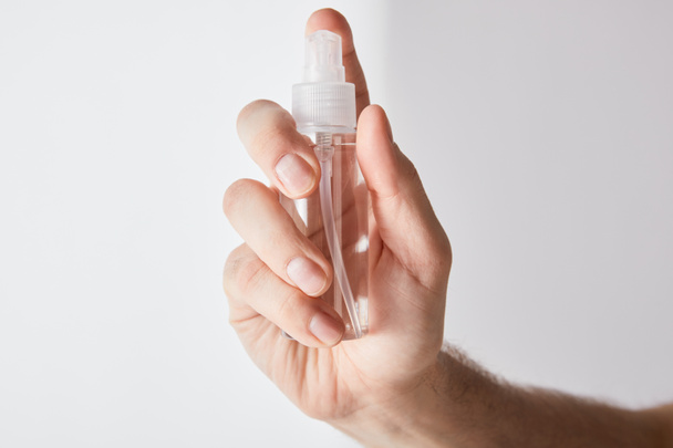 cropped view of man holding hand sanitizer in spray bottle on grey background - Photo, Image