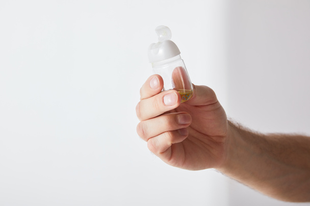 cropped view of man holding hand sanitizer on grey background - Foto, Imagen