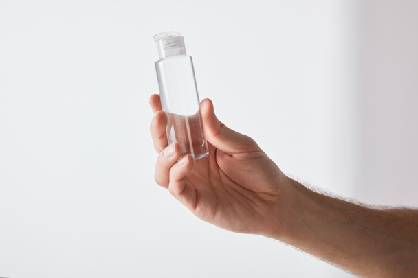 cropped view of man holding hand sanitizer on grey background - Photo, Image