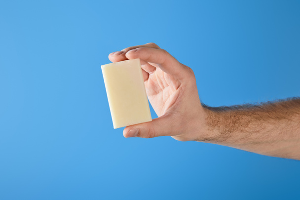 cropped view of man holding soap isolated on blue - Фото, изображение
