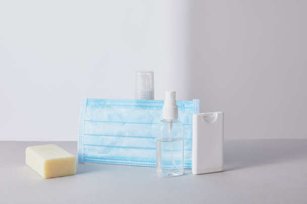 desinfectante de manos en frascos, máscara médica y jabón antibacteriano sobre fondo blanco
 - Foto, imagen