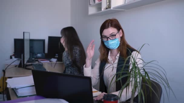 health protection, female employee in medical mask uses an antiseptic to prevent virus and infection in an office near sick colleague - Πλάνα, βίντεο