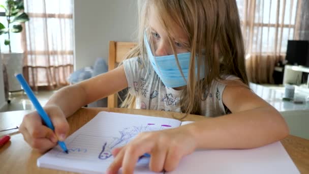 Παιδί με μπλε μάσκα προσώπου ζωγραφίζει στο σπίτι - Πλάνα, βίντεο