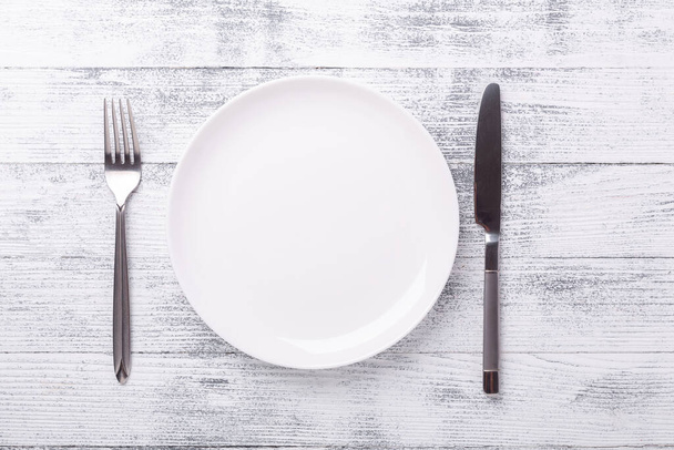 Empty white plate and cutlery on wooden background. Copy space. Top view - Image - Fotó, kép