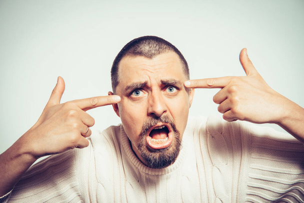 Nahaufnahme Porträt eines wütenden Mannes, der mit dem Finger gegen seine Schläfe gestikuliert, bist du verrückt? - Foto, Bild