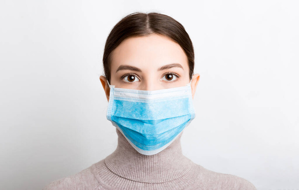 白地に医療マスクをした若い女性の肖像画。健康を守るんだ。コロナウイルスの概念. - 写真・画像