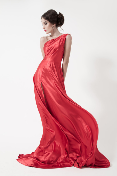 Νεαρή όμορφη γυναίκα με φτερουγισμένο κόκκινο φόρεμα. - Φωτογραφία, εικόνα