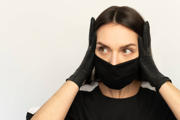 Coronavirus, una joven con una máscara protectora negra y guantes negros, vestida con ropa negra
 - Foto, Imagen