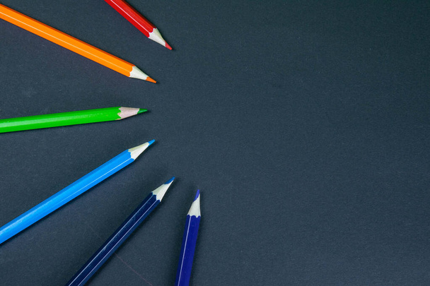 Kleurrijke potloden gerangschikt in een golf geïsoleerd over zwarte achtergrond. - Foto, afbeelding
