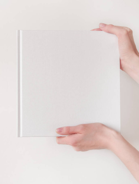 White book mockup. Square empty book. Album with clean pages in hands of woman. Clean book cover mock up - Fotó, kép