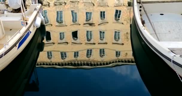 Boats moored on waterway and antique building reflected on water - Footage, Video