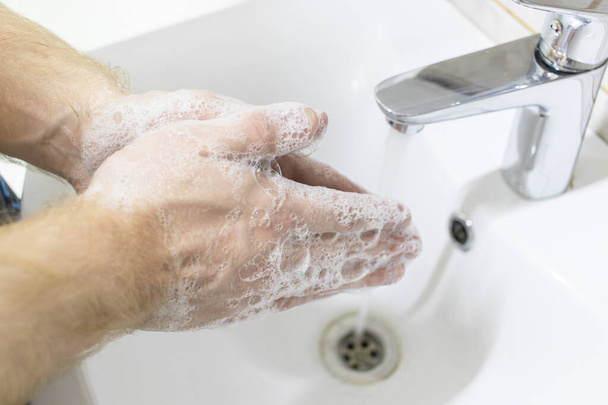 Hygiene concept. Washing hands with soap. Man soaps his hands to prevent virus in the white shell - Foto, immagini