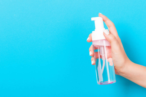 Zbliżenie kosmetyki spray w kobiecej dłoni na niebieskim tle z miejsca do kopiowania. - Zdjęcie, obraz