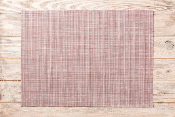 Top view of textile brown mat for dinner on wooden background with copy space. - Photo, Image