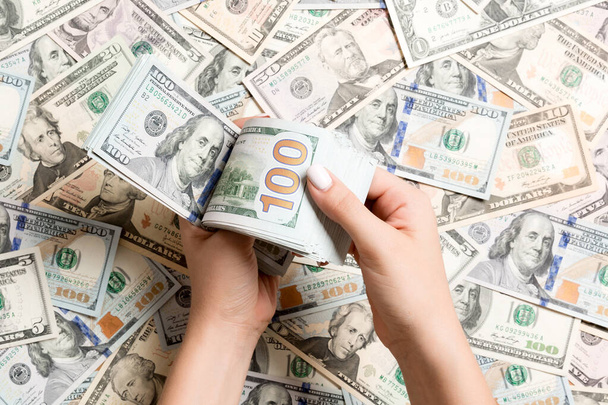 Вид зверху на жіночі руки, які рахують гроші на різному фоні долара. Концепція боргу. Інвестиційна концепція
. - Фото, зображення