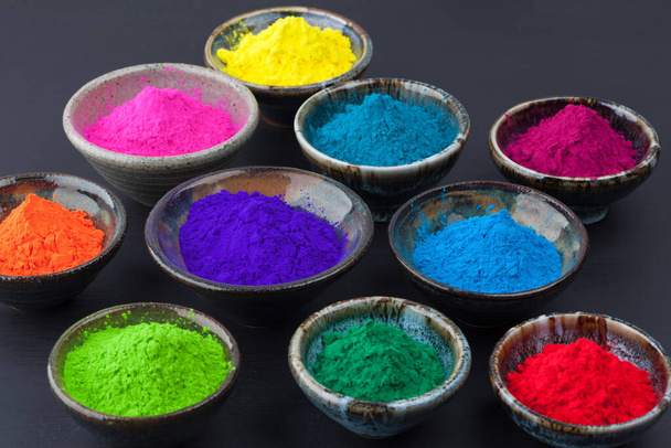 Colorful Holi powder in cups on grungy black chalkboard closoeup. Shallow depth of field. - Foto, Imagem