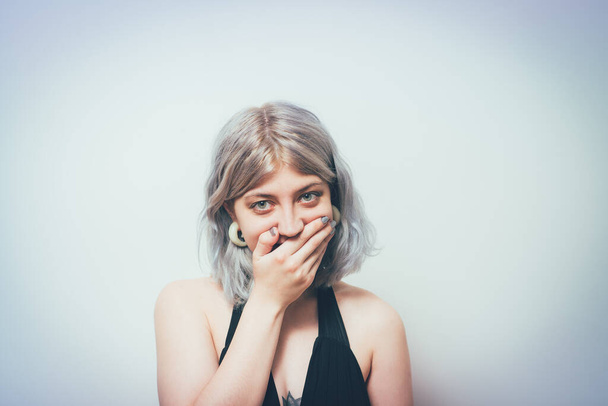 Successful stylish girl covers her mouth with her hands, isolated in the studio - Foto, immagini