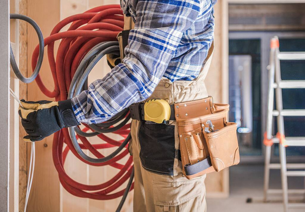 Kavkazský dělník s elektrickými kabely instalující rezidenční elektrické vedení v domě. - Fotografie, Obrázek