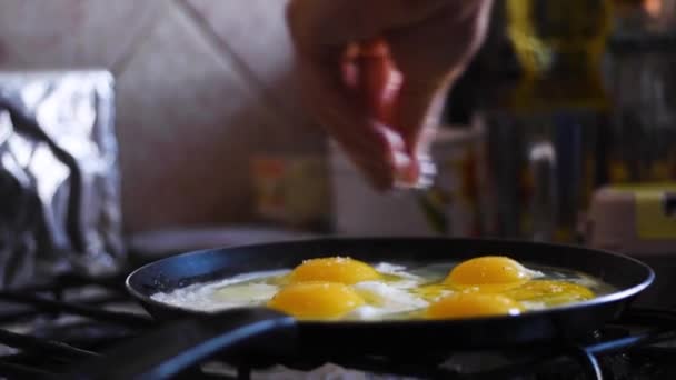 Smażone jajka na patelni, dziewczyna posoliła jajka - Materiał filmowy, wideo