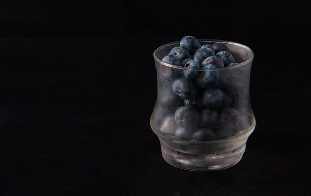 Blueberries in a frosty glass isolated on black. - Photo, image
