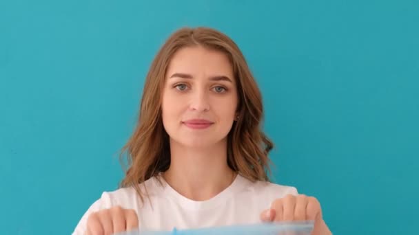 Calm young woman putting on blue medical hat - Footage, Video