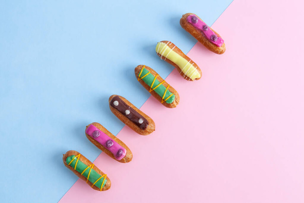 Top view of French eclairs placed diagonally on blue and pink background with copy space - Zdjęcie, obraz