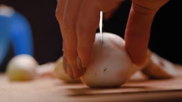 vrouwelijke handen met mooie manicure op de vingers gesneden champignons met een keukenmes op een blauwe kunststof snijplank, close-up. Champignon. vrouw bereidt eten thuis voor - Video