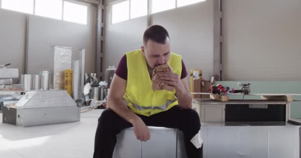 Muž, zabývající se stavebnictvím, si chce dát pauzu a sníst ne příliš chutný a upravený sendvič. - Záběry, video