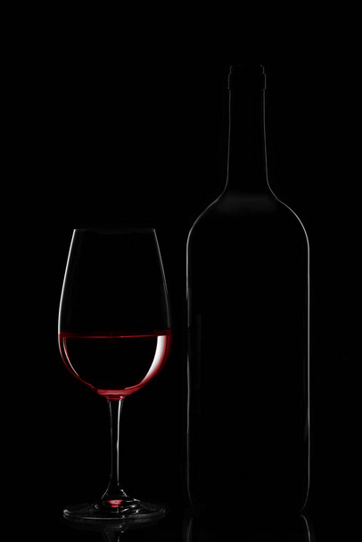 Red wine bottle and wine glass on black background - Photo, Image