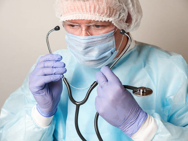 Doctor wearing protective gear gets ready to put his stethoscope to use - Photo, image