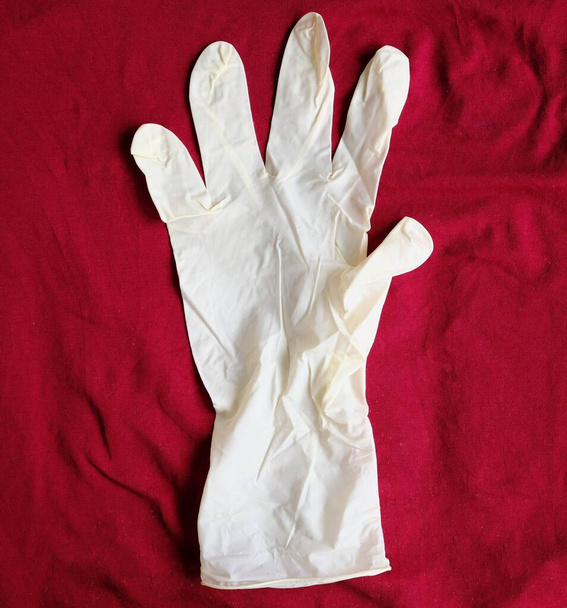 White, latex gloves on a red background. Hand protection against infections, viruses, germs. Isolation of the skin from coronavirus. - Photo, Image