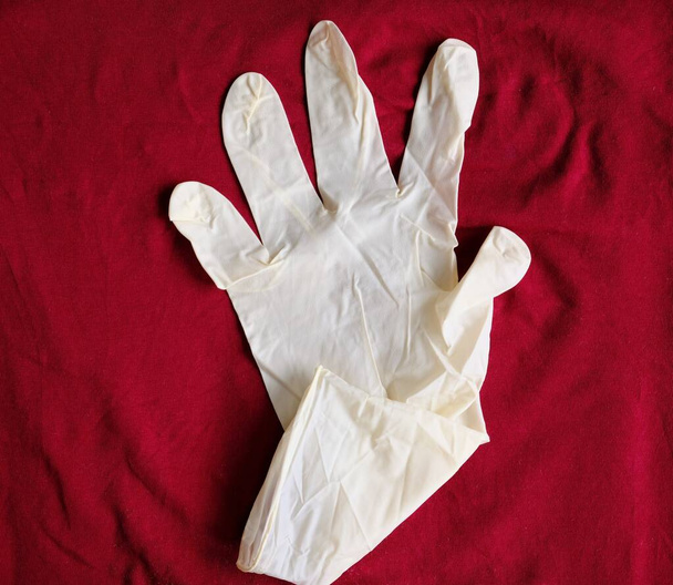 Guantes blancos de látex sobre fondo rojo. Protección de las manos contra infecciones, virus, gérmenes. Aislamiento de la piel del coronavirus
. - Foto, Imagen
