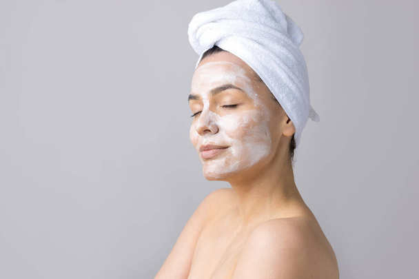 Beauty portrait of woman in white towel on head applies cream to the face. Skincare cleansing eco organic cosmetic spa relax concept. - Foto, Imagem