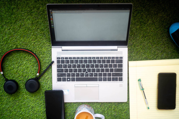 Top-Down-Aufnahme eines Laptops mit Kopfhörer, Mobiltelefon, Notizblock mit Stift und einem drahtlosen Lautsprecher zum Arbeiten aus der Ferne oder von zu Hause aus - Foto, Bild