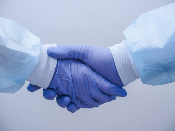 Handshake of two doctors' hands in medical gloves - Foto, afbeelding