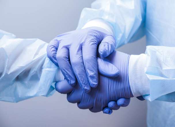 Handshake of two doctors' hands in medical gloves - Foto, afbeelding