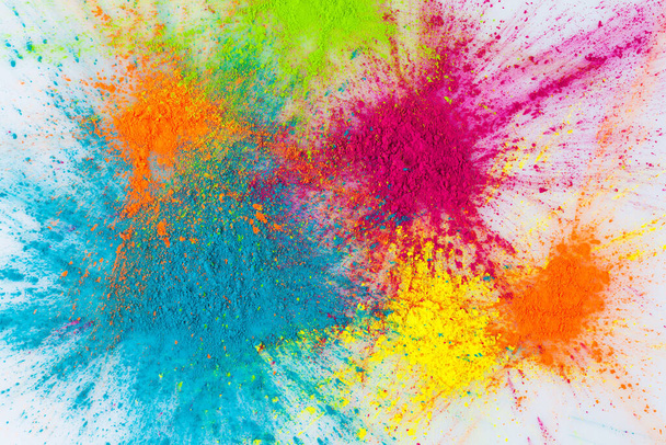 Color explosion concept. Colorful Holi powder exploding on white background closeup. - 写真・画像