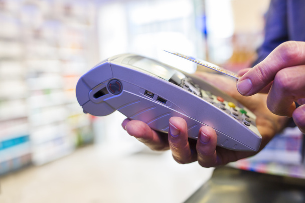 Hombre pagando con tecnología NFC en tarjeta de crédito, en farmacia
 - Foto, Imagen
