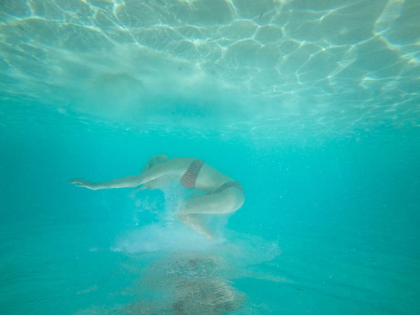 Under water photo of a woman in bikini diving in turquoise sea water. - Zdjęcie, obraz