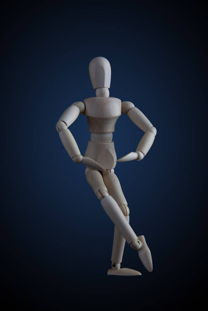 Wooden figurine crossing legs in elegant dancing move on dark background - Фото, зображення