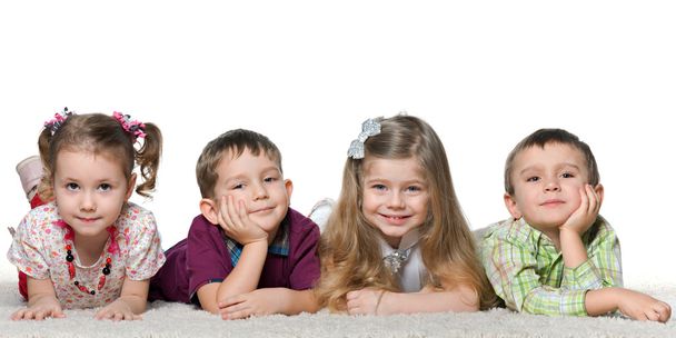 Quatro crianças deitadas no tapete
 - Foto, Imagem