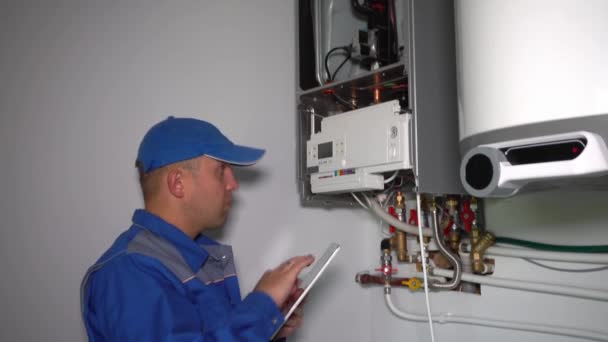 Ingeniero hombre con la computadora de la tableta de reparación de sistema de calentador de gas
 - Imágenes, Vídeo