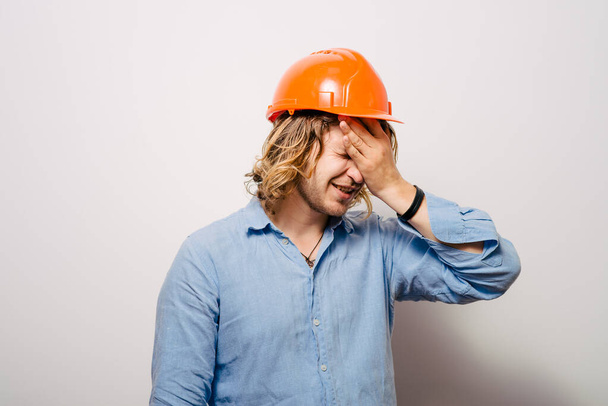 Tired young manual worker - builder, isolated on gray background, close-up studio shot - 写真・画像