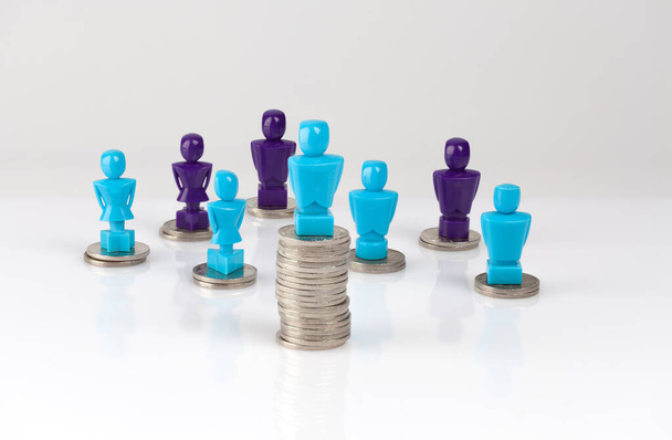 Wage gap and unequal money distribution concept shown with male and female figurines standing on coin piles - Foto, immagini