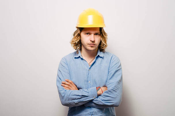 Handsome young man with protective helmet on his head and arms crossed - Фото, изображение