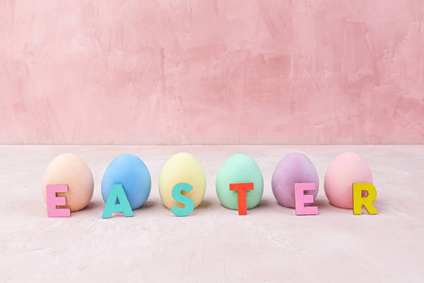 Colorful Easter eggs with Easter text on pink background with copy space - Φωτογραφία, εικόνα