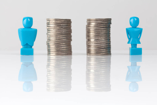 Male and female figurines standing next to equal piles of coins. Income equality concept. - Foto, Imagem