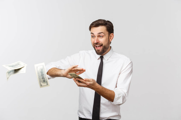 Portret van een gelukkige jonge zakenman die bankbiljetten weggooit die geïsoleerd zijn over een grijze achtergrond. - Foto, afbeelding