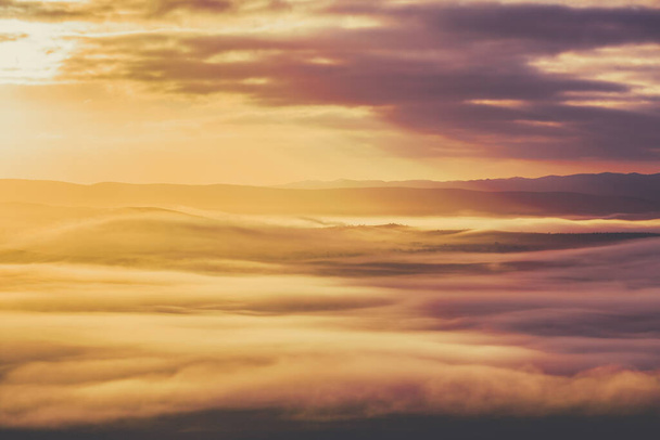Low clouds covering mountain ridge at sunrise - Foto, immagini