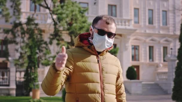 In the middle of empty street man with a protective mask on his face suggesting to all people to wearing the mask on this quarantine of the Coronavirus - Video, Çekim